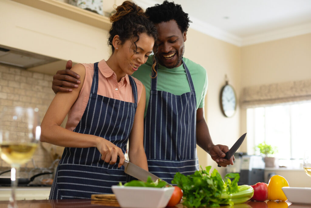 Happy young multiracial couple cooking meal together at kitchen island. people, togetherness and cooking concept, unaltered.