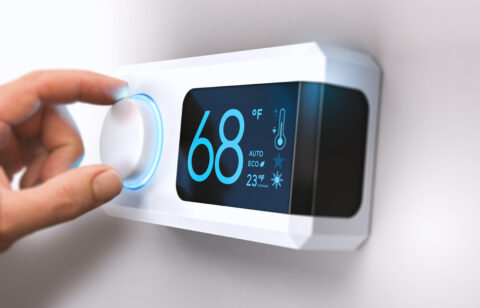 hand turning down temperature for home energy savings