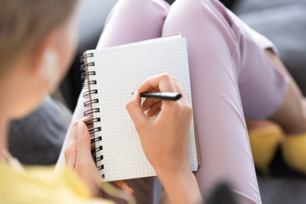 selective focus of woman writing in empty textbook