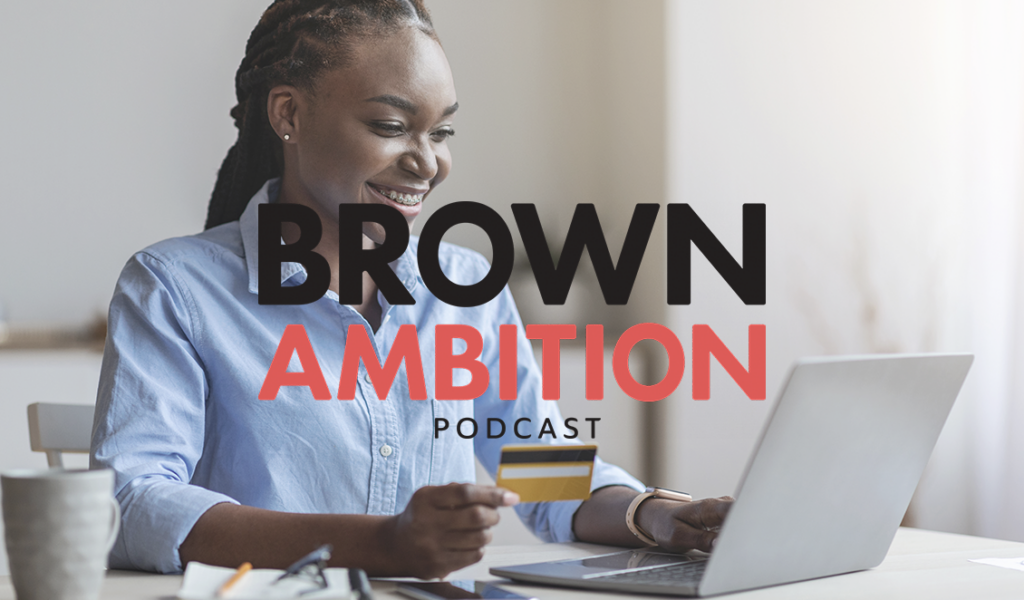 Cover art for the Brown Ambition Podcast. A woman seated in front of a laptop, holding a credit card and smiling.