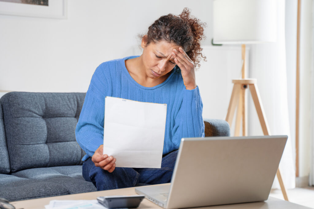 woman rubbing forehead looking at bill