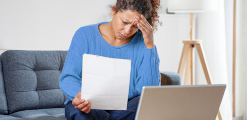 woman rubbing forehead looking at bill