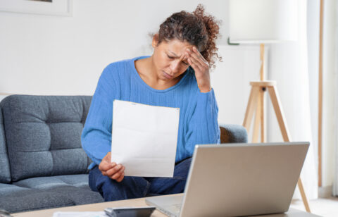 woman rubbing forehead looking at bill