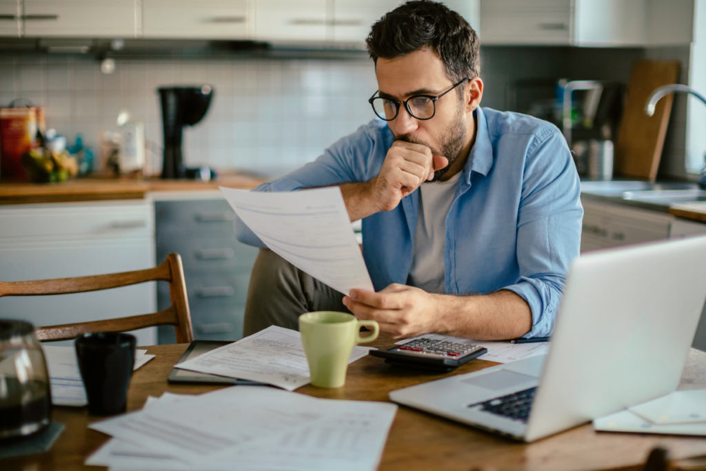 man looking at past due bills at table
