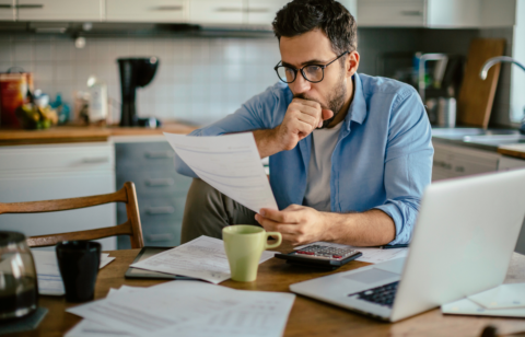 man looking at past due bills at table