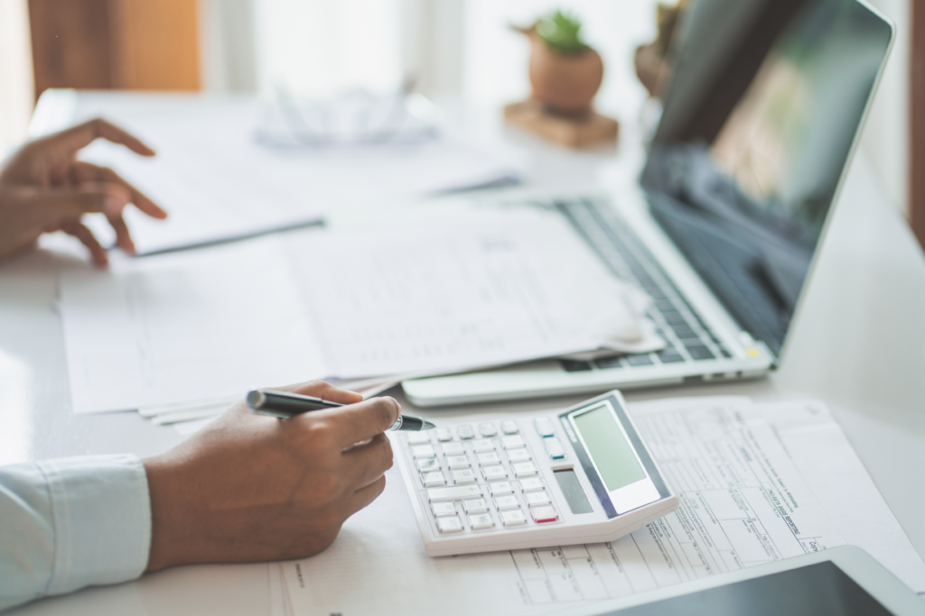 hand holding a pen over a calculator