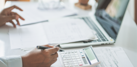 hand holding a pen over a calculator