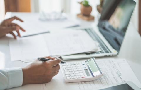 hand holding a pen over a calculator
