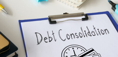 Clipboard with paper labeled “Debt Consolidation” and illustrations of a clock and credit cards, surrounded by office supplies.