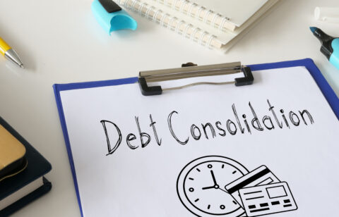 Clipboard with paper labeled βDebt Consolidationβ and illustrations of a clock and credit cards, surrounded by office supplies.