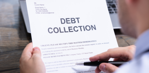 A person holding and reviewing a debt collection notice, which has bold "DEBT COLLECTION" text at the top.