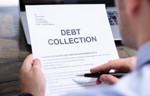 A person holding and reviewing a debt collection notice, which has bold "DEBT COLLECTION" text at the top.