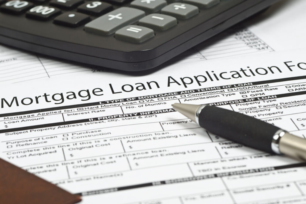 Close-up of a mortgage loan application form with a pen and calculator on top.