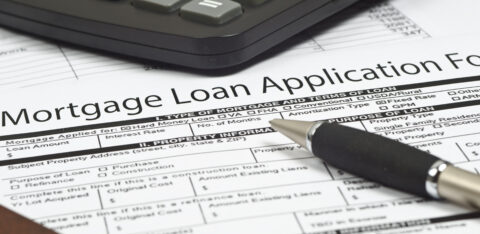 Close-up of a mortgage loan application form with a pen and calculator on top.