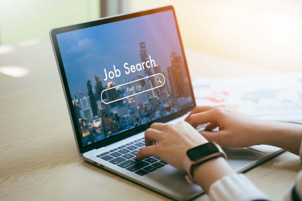 A job seeker browsing for opportunities online, with "Job Search" and a search bar displayed on a laptop screen.