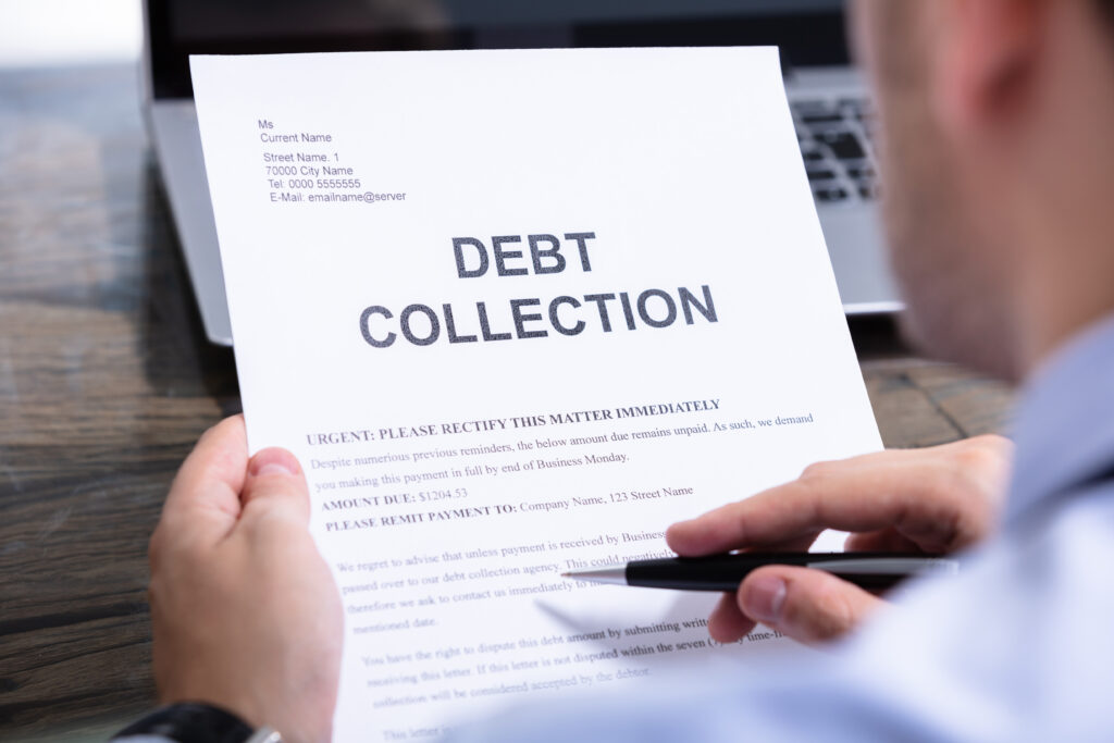 Person holding a debt collection letter while reviewing its contents with a pen in hand.