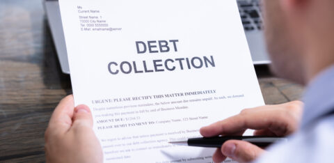 Person holding a debt collection letter while reviewing its contents with a pen in hand.