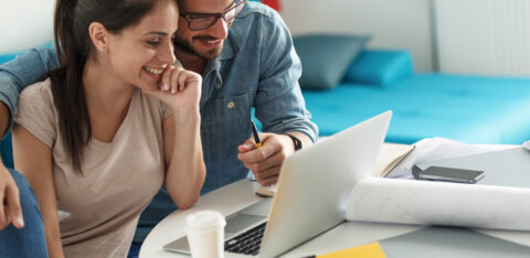 Smiling couple working on financial planning or budgeting together on a laptop.