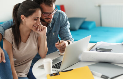 Smiling couple working on financial planning or budgeting together on a laptop.