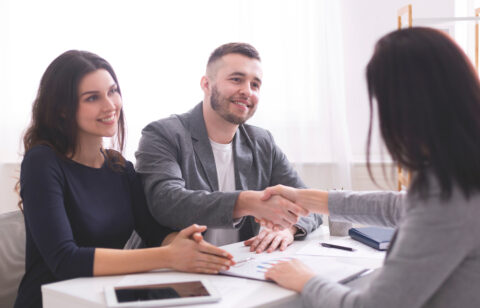 Happy clients shaking hands with a professional consultant, discussing financial or credit counseling services.