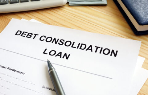Debt consolidation loan application form on a wooden desk with a pen, calculator, and notebook nearby.