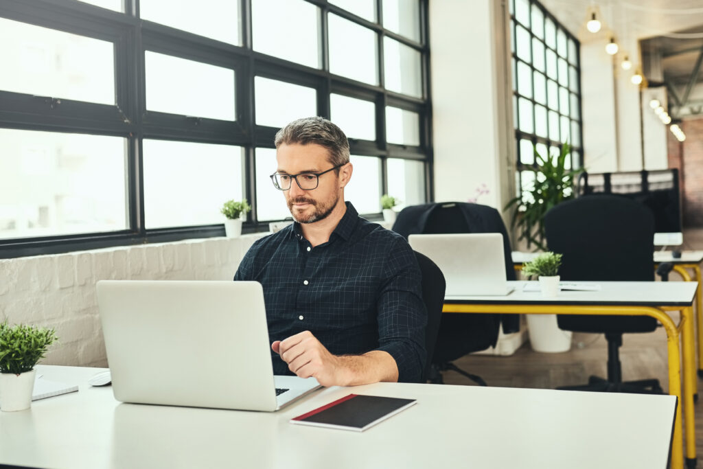 man sitting at desk and looking at computer