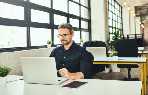 man sitting at desk and looking at computer