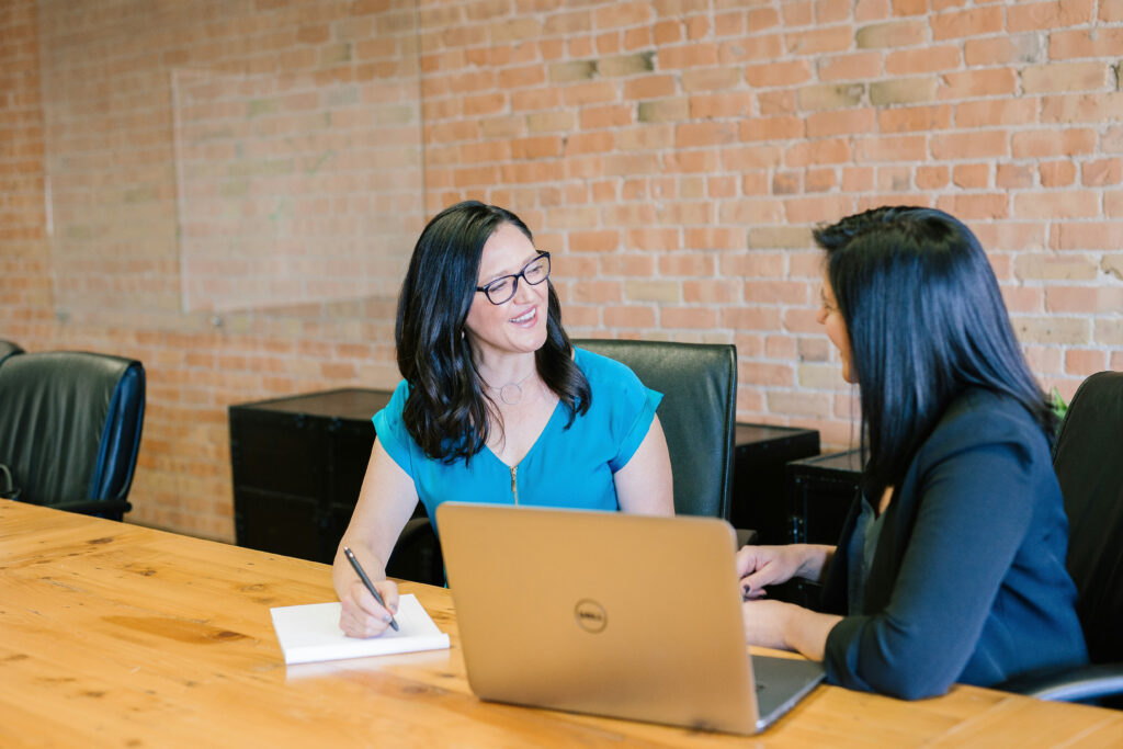 Two professional women having a friendly conversation during a meeting in a modern office.