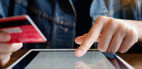 person holding credit card and typing on tablet