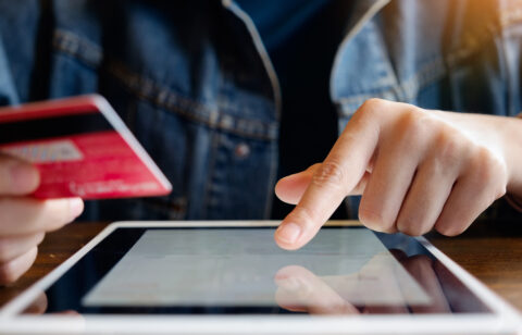 person holding credit card and typing on tablet