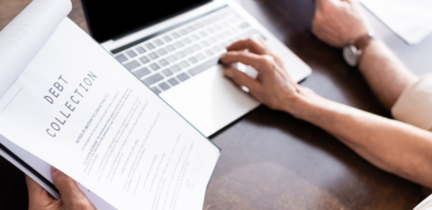 Person reviewing a debt collection notice while using a laptop at a desk