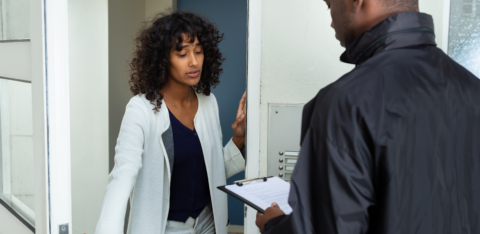 Worried woman answering the door to a man holding a clipboard