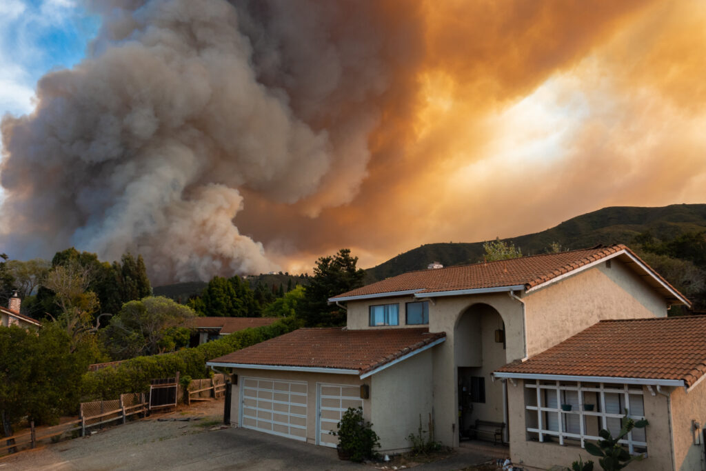 a home with smoke and flames behind it