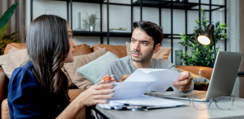 man and woman talking while looking over bills
