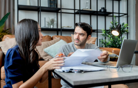 man and woman talking while looking over bills