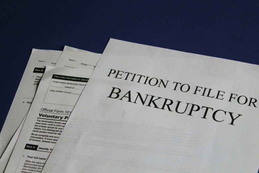 Close-up of bankruptcy petition paperwork on a dark surface, showing official forms for filing Chapter 7 or Chapter 13.