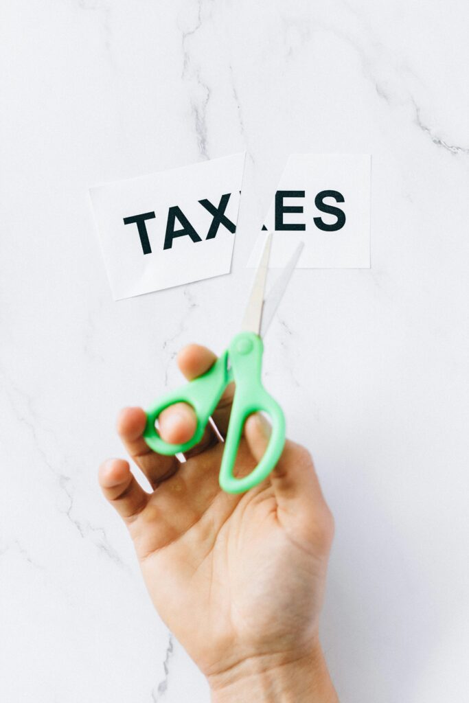 Close-up of a person cutting a “TAXES” sign with scissors