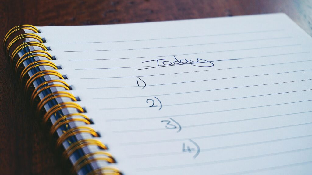 Close-up of a spiral notebook with a handwritten to-do list titled 'Today' and numbered tasks.