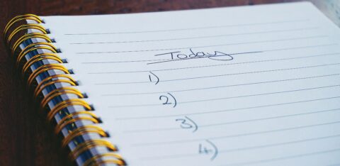 Close-up of a spiral notebook with a handwritten to-do list titled 'Today' and numbered tasks.