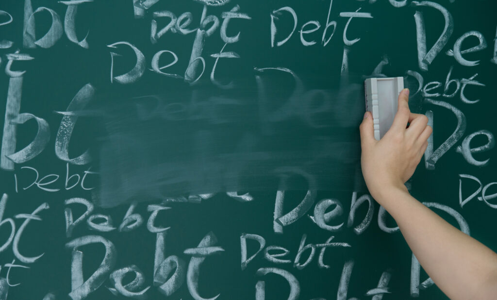 Hand erasing the word “debt” repeatedly written on a chalkboard