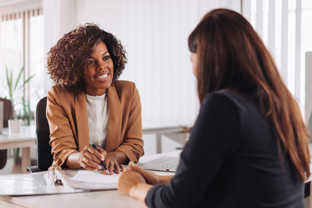 Professional advisor smiling while speaking with a client across a desk
