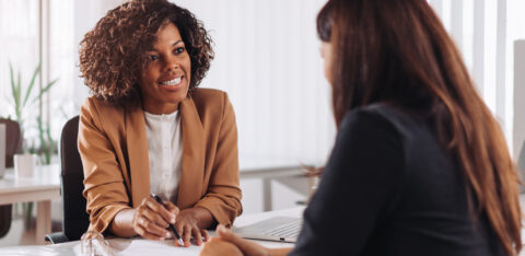 Professional advisor smiling while speaking with a client across a desk