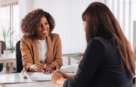 Professional advisor smiling while speaking with a client across a desk