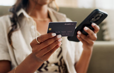 Woman holding a credit card in one hand and a smartphone in the other