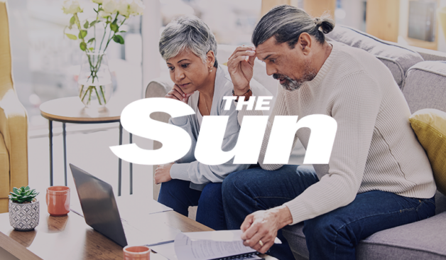 Older couple sitting on a couch reviewing documents and a laptop, with The Sun logo overlayed.