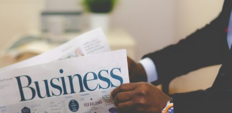 Person in a suit reading the business section of a newspaper