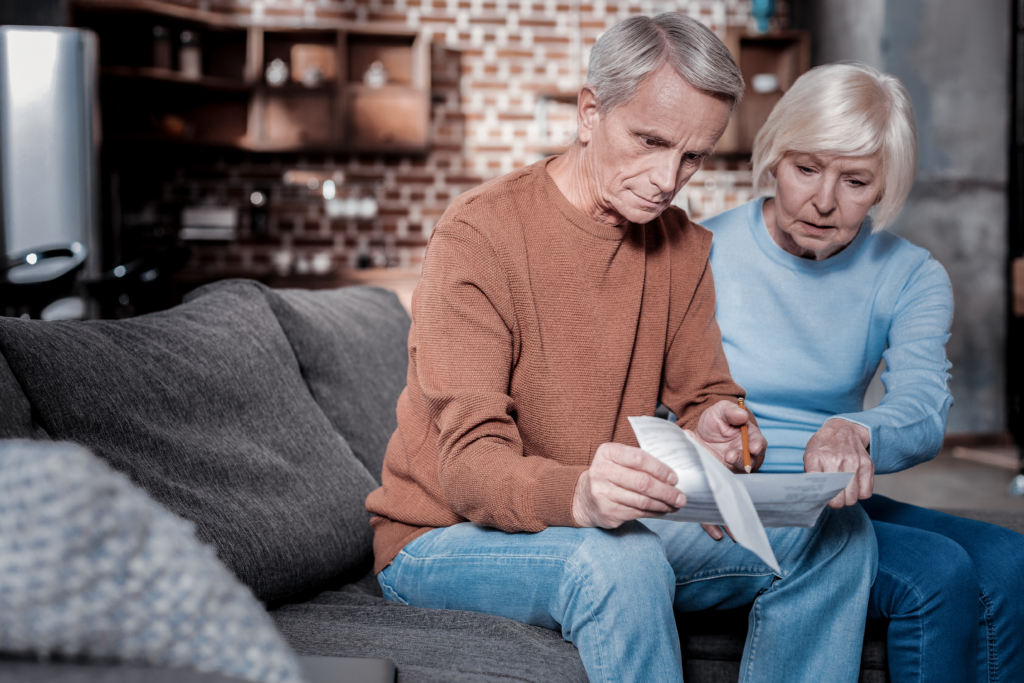Senior couple sitting on a couch reviewing financial documents together.