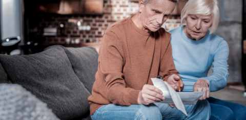 Senior couple sitting on a couch reviewing financial documents together.