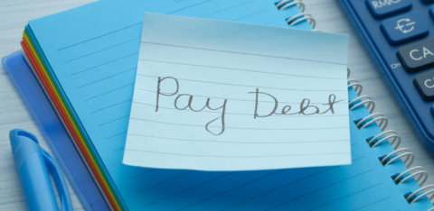 Loan agreement document on a dark desk with a pen, calculator, and stack of cash nearby.