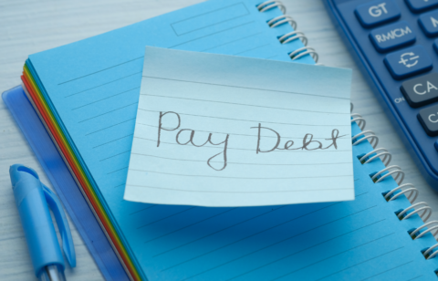Loan agreement document on a dark desk with a pen, calculator, and stack of cash nearby.